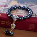 Close-up of polished black beads and silver vajra charm on a vintage red book - Shiny Black Vajra Pestle