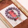 Purple fluted bead bracelet with pink lotus charm and turquoise accents on a card - Purple Lion Glass Lotus Bracelet