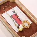 Golden fortune bag charm with orange beads and rutilated quartz on woven cord - Gold Rutilated Quartz Fortune Lock Hanging