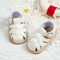 White woven leather baby summer sandals with non-slip rubber soles on beach sand background - 10cm / Braided Hollow Style / White