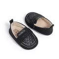 Macro shot of black baby loafers with woven texture and size label 0-6 months - 12-18M / Black