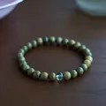 Macro view of sandalwood beads with pale green gemstone bead on a wooden table - 6mm / Green Sandalwood & Green Phantom Quartz