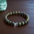 Macro shot of green sandalwood beads with a white jade gourd on a rustic wooden base - 8mm / Green Sandalwood & White Crystal