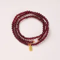 Three-layer garnet bead bracelet with pink accent and golden Fu character charm - White Hetian Jade & Fu Tag Style / 4mm Bead Diameter / Triple-Wrap / Burgundy