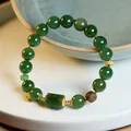 Macro detail of natural jasper beads bracelet with amber and gold Fu charm on ceramic tray - 10mm Green Jade Agarwood Square Silver Bracelet