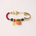 Detailed view of a gold zodiac horse brooch with red rope, gourd, and fortune charms - Persimmon Fortune Style Brooch