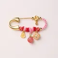 Close-up of golden safety pin brooch with Chinese fortune pendants and red cord - Peach and Gourd Style