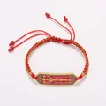 Détail du bracelet tressé rouge avec breloque dorée gravée et perles de protection - Corde à Main Épi de Blé Agate Rouge Plaque Tai Sui