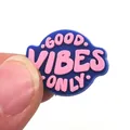 Dettaglio dell'accessorio per zoccoli in PVC Good Vibes Only tenuto tra le dita - Stile Solo Vibrazioni Positive (14)
