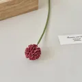 Artificial burgundy globe flower with green stem on a minimalist neutral background - Rose Red