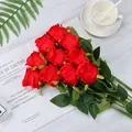 Vibrant red silk artificial rose bouquet with deep green leaves on marble background - Red