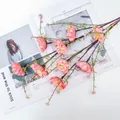 Nahaufnahme von künstlichen rosa Rhododendronblüten mit grünen Blättern auf weißem Tisch - Rosa