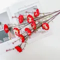 Nahaufnahme von künstlichen roten Seidenblumen mit Blättern und Beeren auf weißem Tisch - Rot