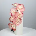 Künstlicher Orchideenzweig mit acht rosa Blütenblättern in einer weißen Wellenvase - Herbstrosa