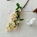 Artificial lilac bouquet in soft pink with green leaves on white textured fabric - Champagne