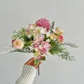 Brautstrauß mit rosa Hortensien und beigen Rosen mit üppigen grünen Blättern in der Hand - Lila