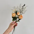 Kunstboeket met oranje rozen, witte madeliefjes en eucalyptus vastgehouden in de hand - Geel