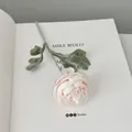 Single light pink faux ranunculus stem on white book for elegant home table decor - Light Pink
