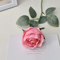 Single pink silk artificial rose with long stem and green leaves on a beige background - Deep Pink