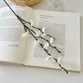 Rama de flor de ciruelo artificial blanca de 55cm sobre un libro abierto antiguo - Mini Flor de Invierno Blanco