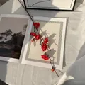 Rama de flor de ciruelo artificial roja vibrante sobre tela blanca con accesorios de arte - Ruyi Flor de Ciruelo Rojo