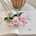 Five stems of artificial pink silk roses with green leaves on white book pages - Flamingo Pink