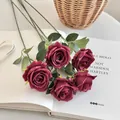 Artificial bouquet of five dark red silk roses with green leaves on an open book - Burgundy