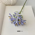 Künstliche Agapanthus Blume in Lila und Blau Farbverlauf auf einem offenen weißen Buch - Blau