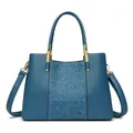 Navy blue leather tote bag with embossed floral pattern and gold metal hardware - Blue