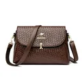 Dark brown woven crossbody bag featuring a golden kangaroo logo and metal chain accents - Brown