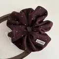 Dettaglio di elastico scrunchie in lana bordeaux a pois su vassoio di legno - Rosso scuro