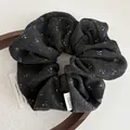 Détail d'un chouchou en tricot gris à fleurs avec texture douce et logo Ailuoma - Gris & Noir
