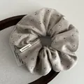 Detailansicht eines beigen Strick-Haargummis mit zartem braunem Blumenmuster-Design - Beige Aprikose