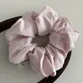 Detailopname van een roze geruite scrunchie van katoen op een stoffen dienblad - Roze