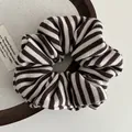Detalle de un coletero de punto con rayas marrones y beige sobre una bandeja de madera - Marrón