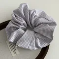 Detailopname van paarse gingham scrunchie met zachte stof op houten dienblad - Taropaars