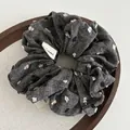 Close-up of textured scrunchie with colorful polka dots and a fabric label on wood - Dark Grey