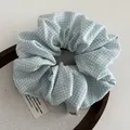 Detailweergave van de blauw-witte ruitjes scrunchie met Andrea geweven label - Blauw