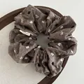 Close-up of brown linen scrunchie with colorful dots and a small woven side label - Light Coffee