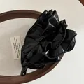 Detail der eleganten schwarzen Bananenspange aus Kunstleder mit geflochtener Kante - Schwarz