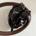 Makroansicht der dunkelbraunen Leder-Bananenspange mit eleganten Faltenstrukturen - Dunkelkaffee