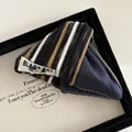 Macro detail of striped cat ear hair clip featuring fabric texture and logo tag - Denim Blue