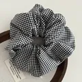 Detail of a black and white gingham checkered scrunchie on a wooden tray - Black