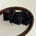 Vue détaillée de la pince banane nœud à pois sur un plateau de présentation en lin - Noir marine