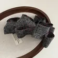 Détail d'une pince à cheveux en tweed à pois sur un plateau en bois vintage - Gris à Losanges