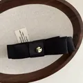 Primo piano di un elegante fiocco in raso nero con emblema in metallo dorato - Raso Nero Classico