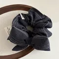 Dettaglio scrunchie in denim a righe con fiocco e targhetta su vassoio in legno - Blu Denim