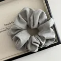 Close-up of a grey knitted scrunchie with soft ribbed texture in a minimalist tray - Light Gray