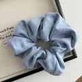 Detailed close-up of light blue knitted scrunchie fabric texture on a white tray - Blue
