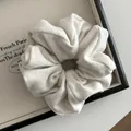Close-up of cream ribbed knit scrunchie with textured fabric on a vintage tray - Off-white